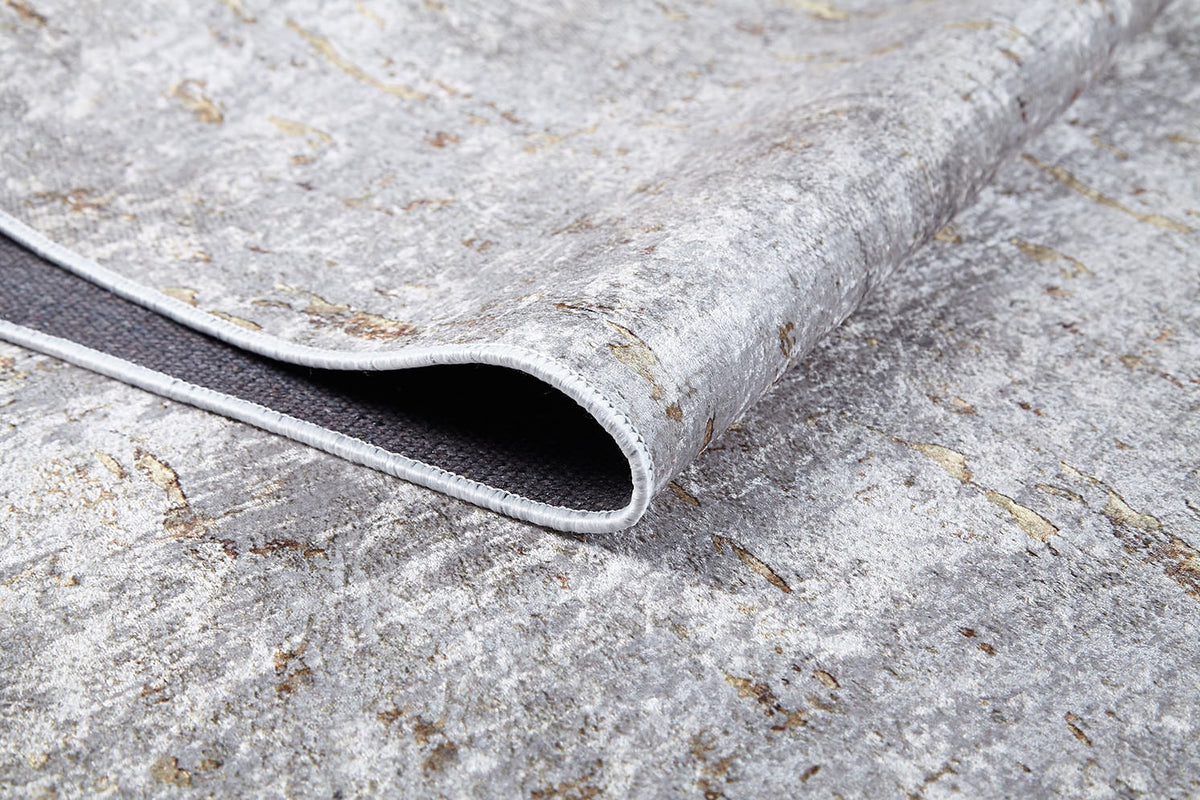 Close-up of the Berry Blossom - Washable Rug - JR1818 (Custom Size) in textured gray-anthracite with a folded corner, showing its dark non-slip backing. This flat weave rug has a marbled, stone-like pattern for stylish spaces.