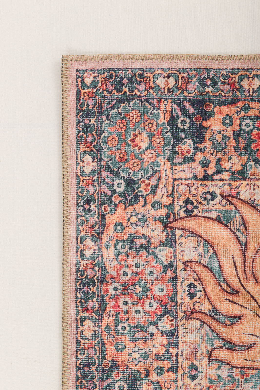 A close-up of the Blazefang Myth - Washable Rug - JR0049 shows its detailed floral border in blue, pink, and orange with part of an abstract sun-inspired geometric pattern on the right.