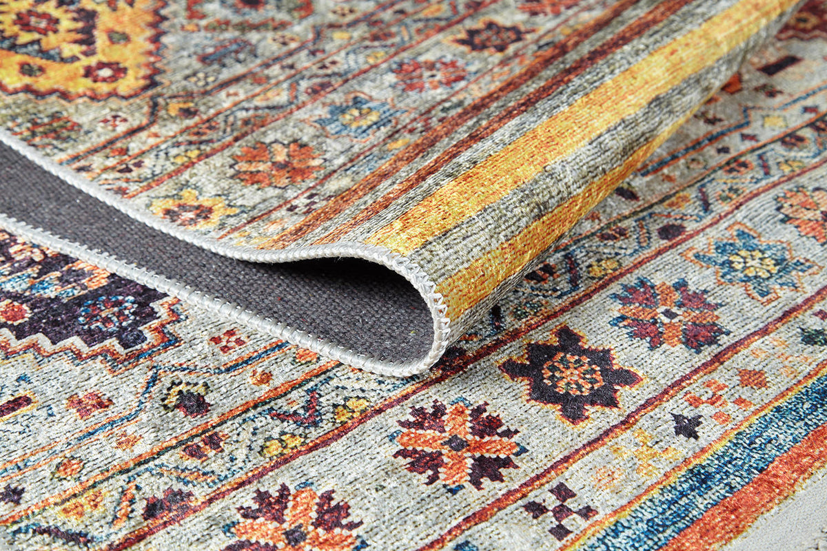 A close-up of the Bohemian Bouquet - Washable Rug - JR5090 (Custom Size) shows vibrant floral and geometric patterns in yellow, orange, blue, and red on gray, with a folded corner highlighting its easy-care flat weave design.