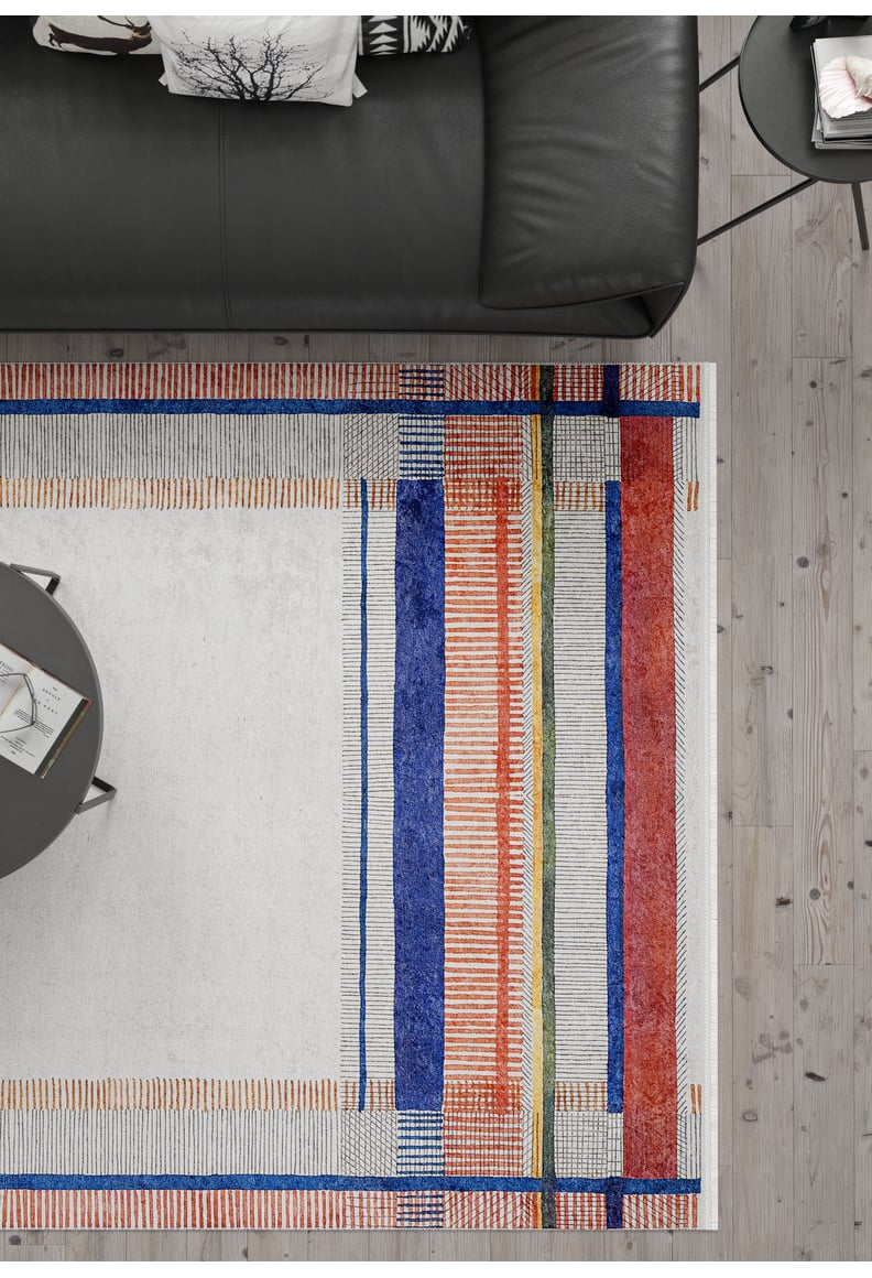 Modern living room with a black sofa, round coffee table, and light wood floor. The Bohemian Nightscape - Washable Rug - JR1701 (Custom Size) features bold geometric patterns in blue, orange, red, and green—ideal for high-traffic areas.