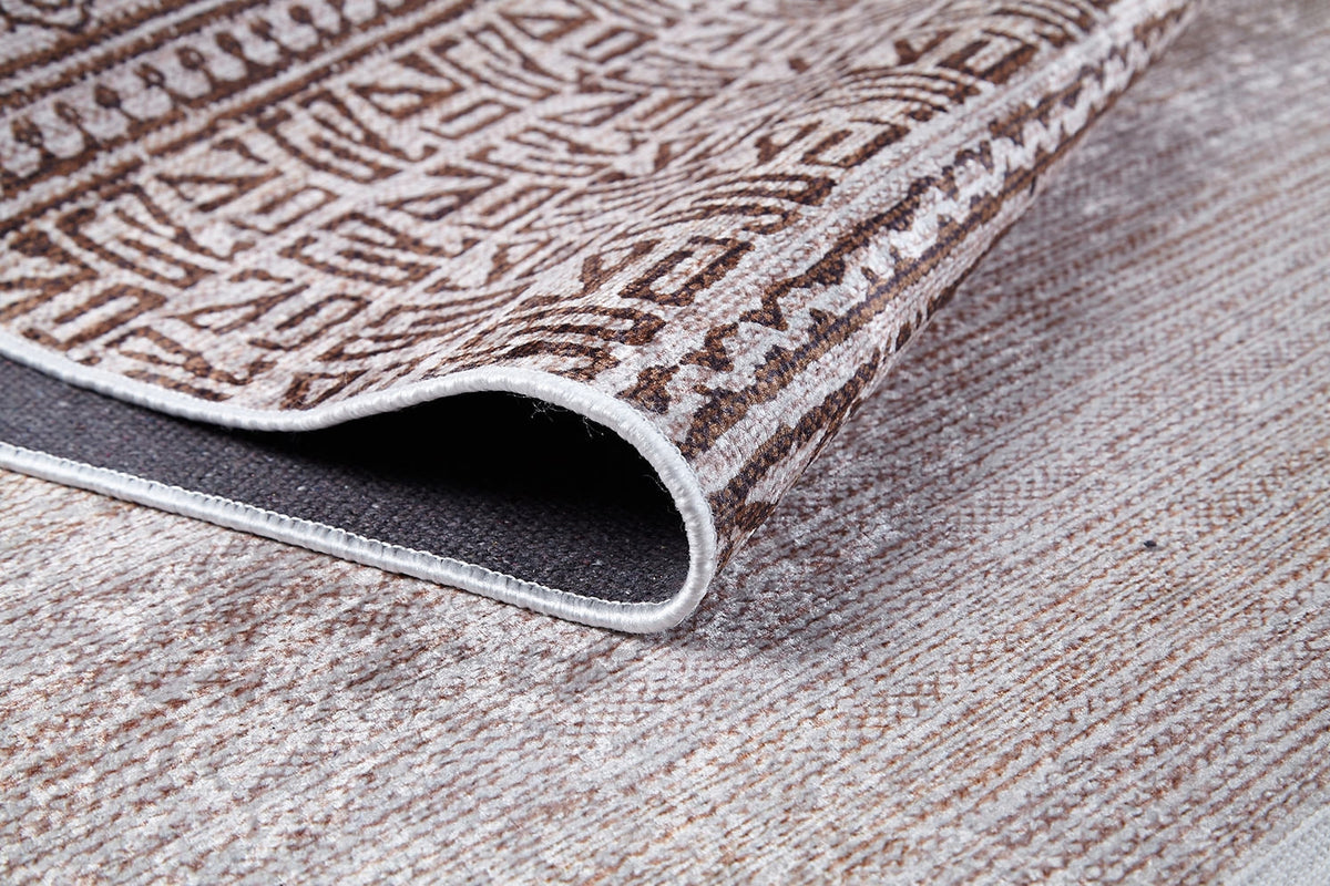 A close-up of the Bohemian Treasure - Washable Rug - JR1586 (Custom Size) shows its textured brown and beige geometric design with a dark non-slip backing, perfect for high-traffic spaces and resting on a matching woven floor.