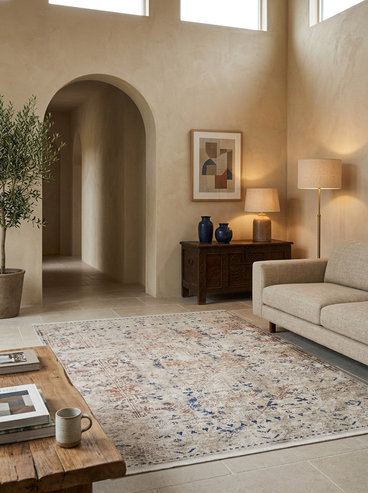 Distressed beige rug with faded blue and rust-colored traditional patterns, styled in a neutral living room.
