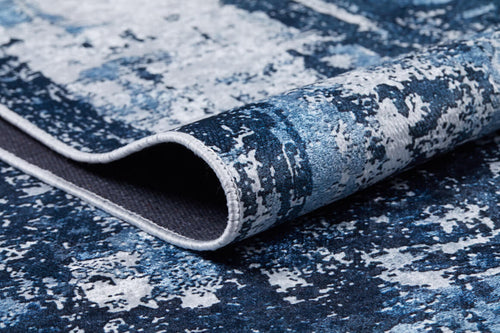 Load image 1 in gallery view. A close-up of the Bold Blooms - Washable Rug - JR836 (Custom Size) in blue with white abstract patterns, showing a folded edge and detailed border stitching—ideal for high-traffic areas and easy to clean.