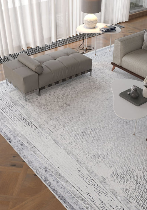 Load image 1 in gallery view. A bright living room showcases the Bold Borderline - Washable Rug - JR1984 (Custom Size), paired with a gray upholstered bench, modern white coffee table, and beige sofa on wood parquet—ideal for high-traffic spaces and sheer curtains.