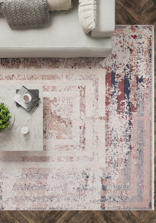 Load image 1 in gallery view. A modern living room viewed from above shows a light gray couch, marble coffee table with a plant, drink, and magazines, on the JR1410 Bold and Geometric washable rug—ideal for high-traffic areas—laid over herringbone wood floors.