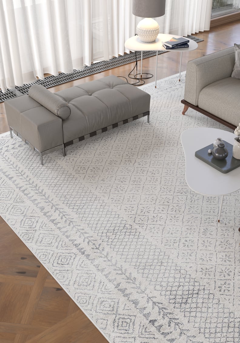Modern living room with the Borderline Brilliance - Washable Rug - JR1987 (Custom Size), a gray bench and sofa, white coffee table with decor, round side table with lamp, and large windows—ideal for high-traffic areas.