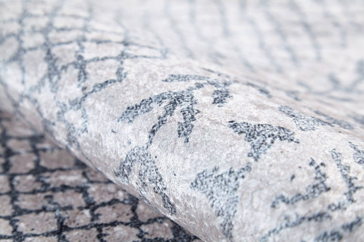 A close-up of the Borderline Brilliance - Washable Rug - JR1987 (Custom Size) shows its soft, slightly shiny gray-anthracite surface with a dark geometric pattern—ideal for high-traffic areas and easy to clean.