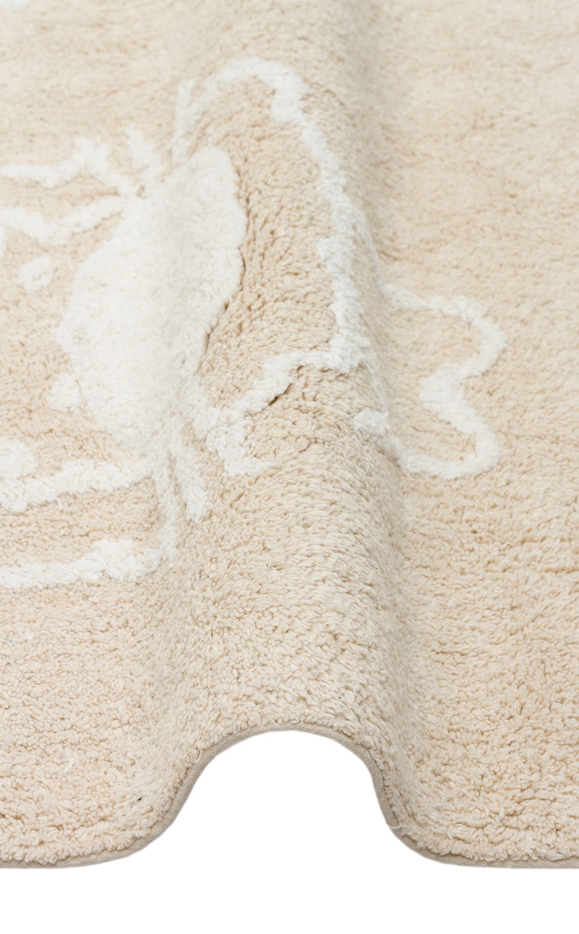 A close-up of the Calm Nest - Washable Shaggy - CBN16 cream beige rug, featuring a subtle white crab design and ultra-soft cotton texture, displayed with a gentle wave in the fabric.