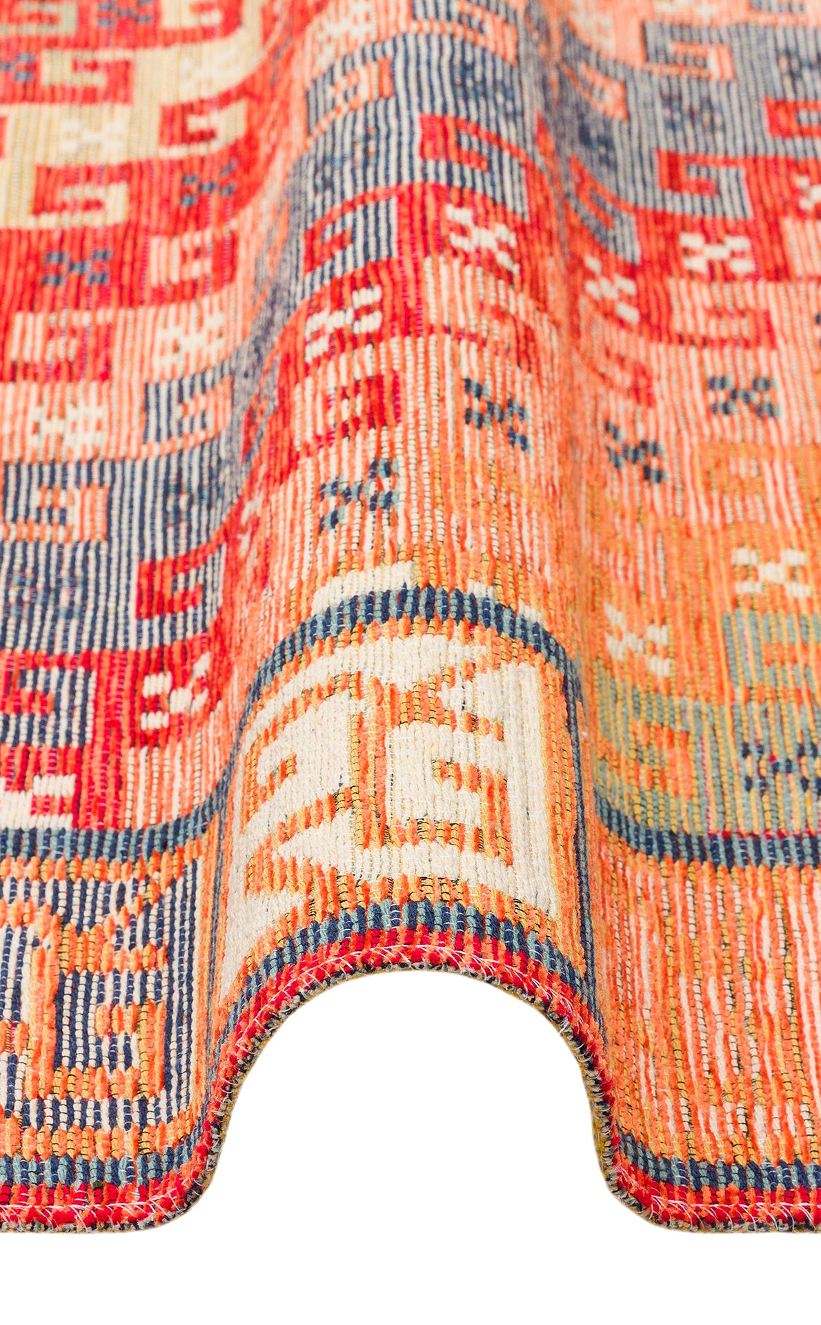 A close-up of the Canyon Shade - Washable Reversible Kilim - NMD11 showcases its vibrant red, orange, blue, and cream geometric patterns, elegantly draped in a wavy curve against a white background.