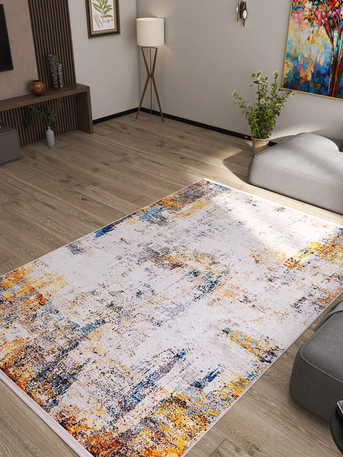 Load image 1 in gallery view. A modern living room with light wood floors, neutral furniture, and the Chromatic Kaleidoscope Washable Rug (JR1483), featuring white, blue, yellow, and orange—ideal for high-traffic areas. Minimalist decor, plants, and vibrant wall art complete the look.