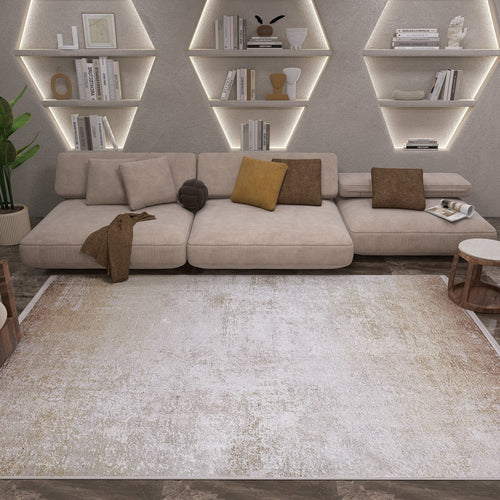 Load image 1 in gallery view. A modern living room features a beige sectional, brown accent pillows, wooden tables, geometric shelves with books and decor softly lit, and the Cinnamon Swirl - Washable Rug - JR425 in cream and beige—perfect for high-traffic areas.