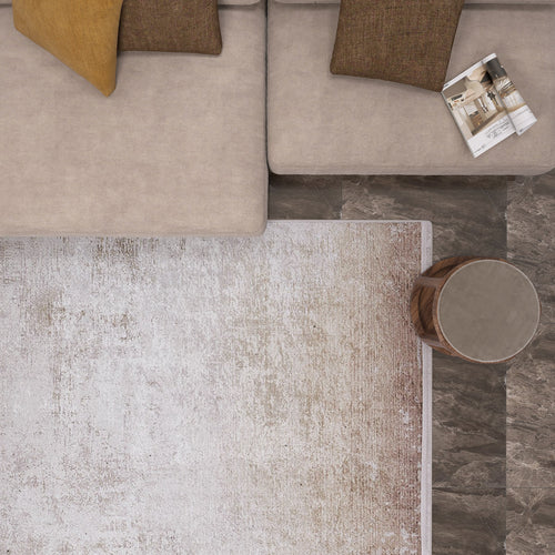 Load image 1 in gallery view. A top-down view of a beige sectional with brown and yellow pillows, an open magazine, a round wood side table, and the Cinnamon Swirl - Washable Rug - JR425—ideal for high-traffic areas—over dark marble-patterned flooring.