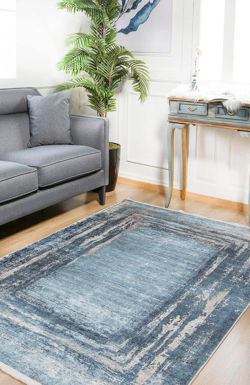 Load image 1 in gallery view. A modern living room featuring a gray sofa, Classic Bordered - Washable Rug - JR1197 (Custom Size) perfect for high-traffic areas, a small plant, vintage blue desk with gold legs, white walls, and framed abstract art for a stylish touch.