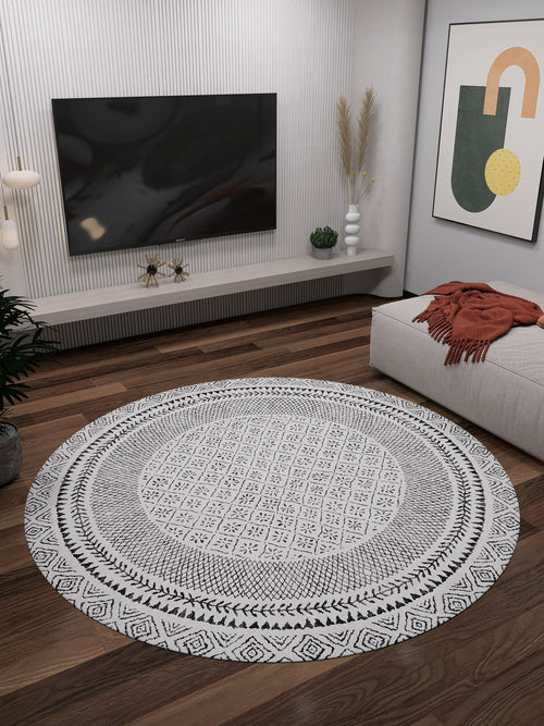 Load image 1 in gallery view. A modern living room with the Classic Contrast - Washable Rug - JR1985 (Custom Size) on wooden floors, a wall-mounted TV, minimalist shelves, potted plant, abstract art, and a sofa draped with an orange throw blanket.