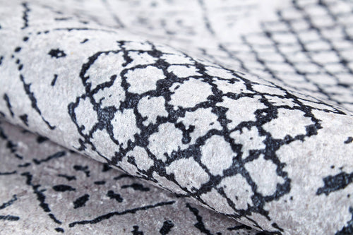 Load image 1 in gallery view. A close-up of the Classic Contrast - Washable Rug - JR1985 (Custom Size), rolled up to showcase its black geometric and abstract pattern on a light gray flat weave with soft texture and visible fibers.
