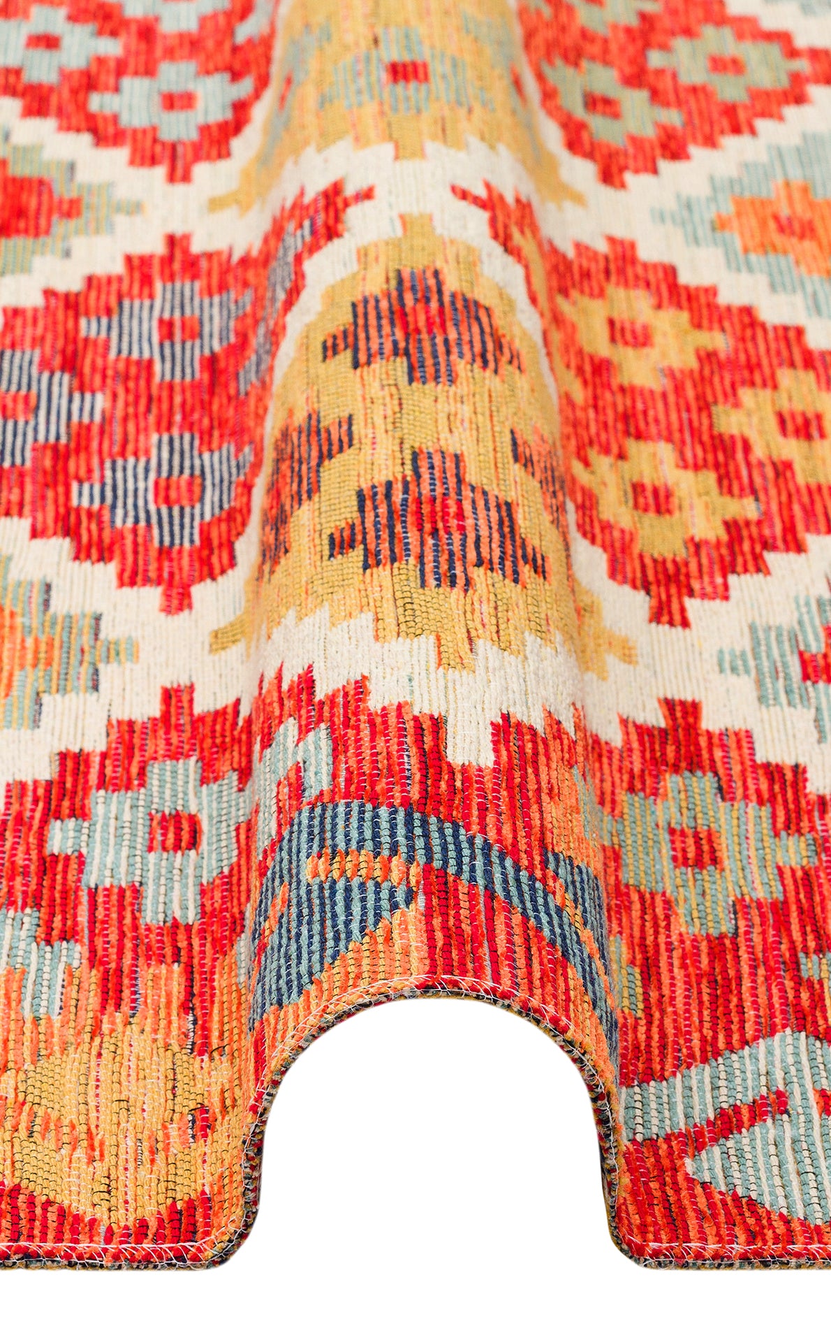 A close-up of the Clay Mark - Washable Reversible Kilim - NMD05 rug, featuring vibrant red, yellow, blue, and cream geometric patterns. The partial fold shows off its rich texture and thickness.