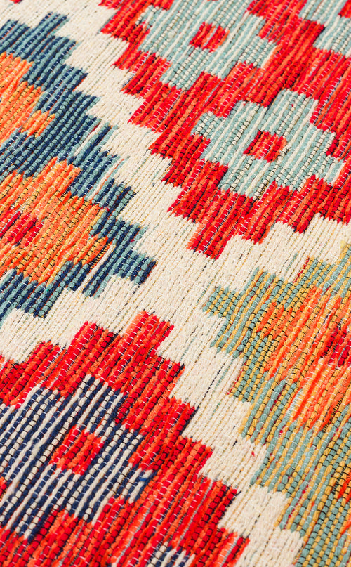 Load image 1 in gallery view. Close-up of the Clay Mark - Washable Reversible Kilim - NMD05 rug, showcasing vibrant red, blue, orange, and cream geometric patterns with zigzags and diamond shapes that highlight its colorful and detailed tribal texture.