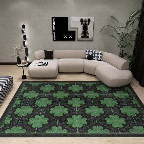 Load image 1 in gallery view. Modern living room featuring the Clover Noir - Washable Rug - JRS012 (Custom Size) with large green four-leaf clovers, ideal for allergy-sensitive and high-traffic spaces. Includes curved beige sofa, black and white pillows, wall art, plants, lamp, and striped ottoman.