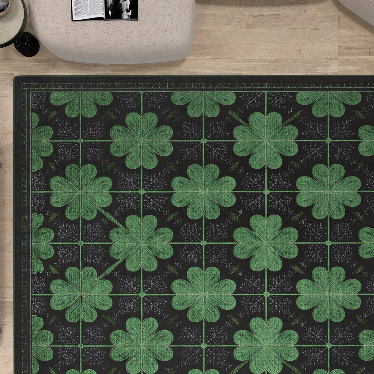 The Clover Noir - Washable Rug - JRS012 (Custom Size) features a black base with green four-leaf clovers, shown on a light wood floor. In the top left corner, part of a beige chair and an open magazine can be seen. Perfect for high-traffic areas.