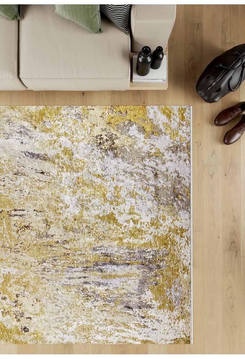 Overhead view of a beige sofa with green cushions, coffee table, brown shoes, and a black bag on light wood floors with the Color Splash - Washable Rug - JR146 in yellow-gold—ideal for high-traffic areas.