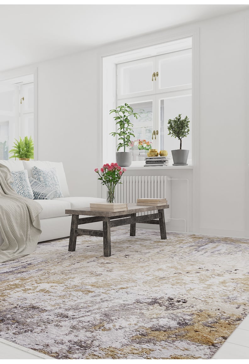 Bright living room with a white sofa, patterned pillows, rustic wooden coffee table, and the Contemporary Canvas - Washable Rug - JR145 (Custom Size) in yellow-gold—perfect for high-traffic areas—with plants by a sunlit window.