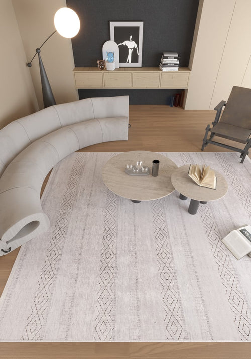 Load image 1 in gallery view. A modern living room features the Contemporary Coordinates - Washable Rug - JR750 (Outlet) US, perfect for high-traffic areas. Its neutral cream and beige tones complement a curved gray sofa, round coffee tables, glassware, and wooden floors.