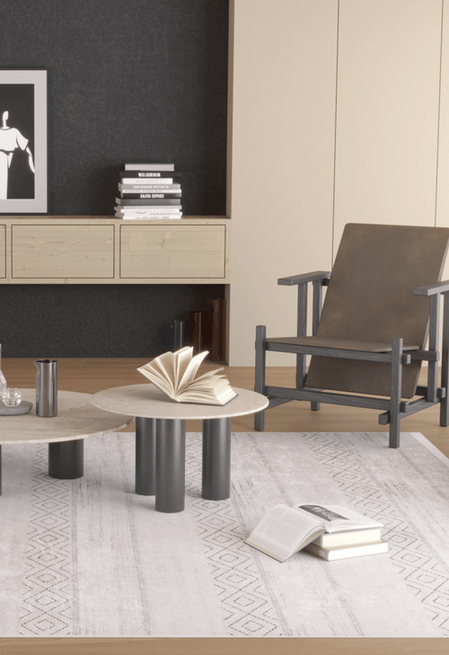Load image 1 in gallery view. A modern living room features a wooden armchair, two round coffee tables, books, a silver vase, framed art above a sideboard, and is grounded by the Contemporary Coordinates - Washable Rug - JR750 in cream and beige flat weave.