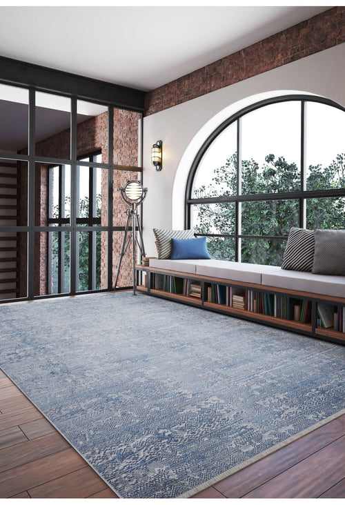 Load image 1 in gallery view. A modern room with a large arched window, brick walls, the Contemporary Serenity - Machine-Washable Rug JR1884 (Custom Size) in blue for high-traffic areas, a cushioned bench, bookshelves below, a vintage floor lamp, and trees visible outside.