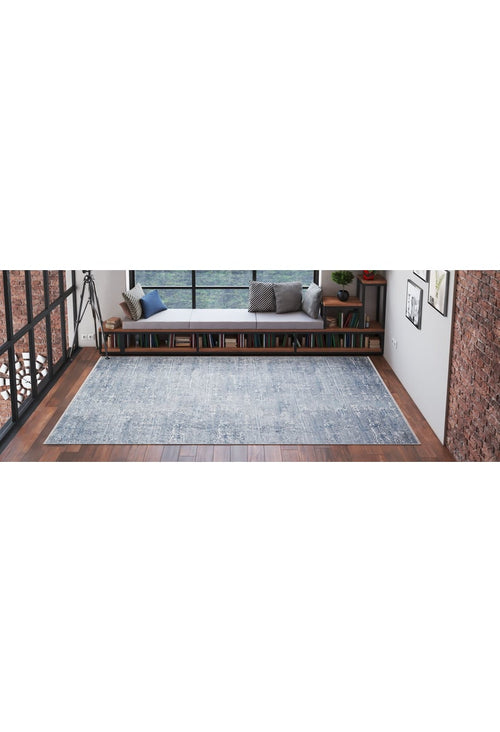 Load image 1 in gallery view. A spacious, modern room with wooden floors and exposed brick walls features the Contemporary Serenity - Machine-Washable Rug JR1884 (Custom Size) in blue—ideal for high-traffic areas—plus a bench with cushions and books by large windows.