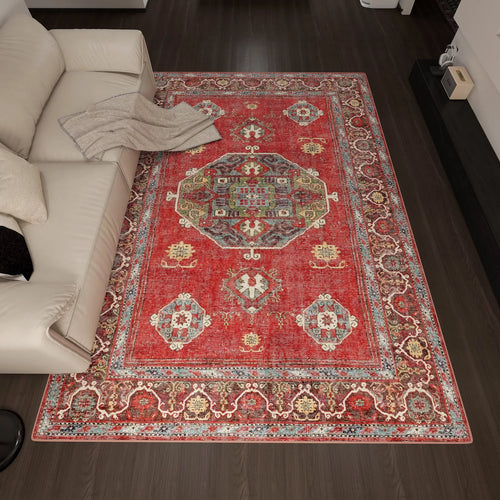 Load image 1 in gallery view. The Crimson Palace - Washable Rug - JRN1041 (Custom Size) with intricate red patterns lies on a dark wood floor next to a light sofa with white and beige cushions and a beige throw, complementing the room’s modern decor.