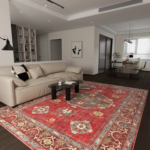 Load image 1 in gallery view. A modern living room features a beige sofa, dark round coffee tables, and the Crimson Palace - Washable Rug - JRN1041 (Custom Size) in rich red on dark wood floors. The open space connects to a dining area and kitchen with white walls and minimalist decor.