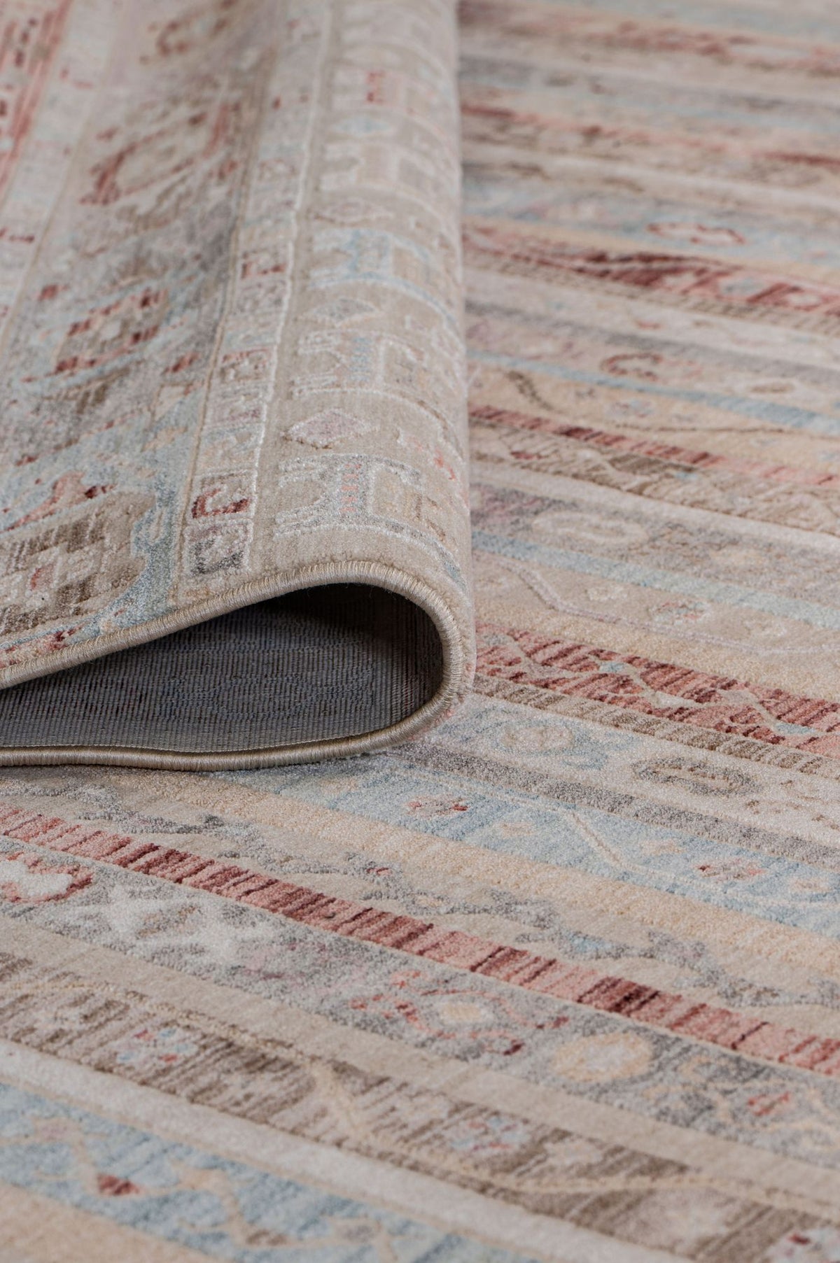 Beige, blue, and terracotta striped rug with a distressed traditional pattern, shown with a corner folded over.