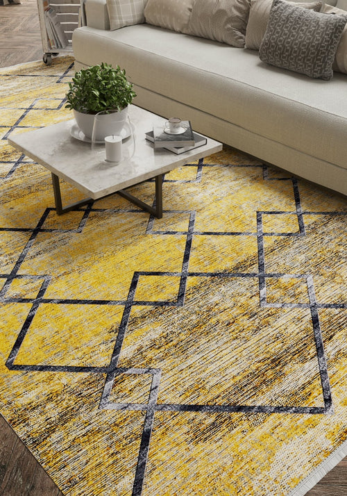 Load image 1 in gallery view. A modern living room features a white sofa, grey patterned pillows, and a marble coffee table with decor. The floor showcases the Crossed Connections - Washable Rug - JR1181 (Outlet) US in yellow-gold with navy geometric lines—ideal for busy spaces.