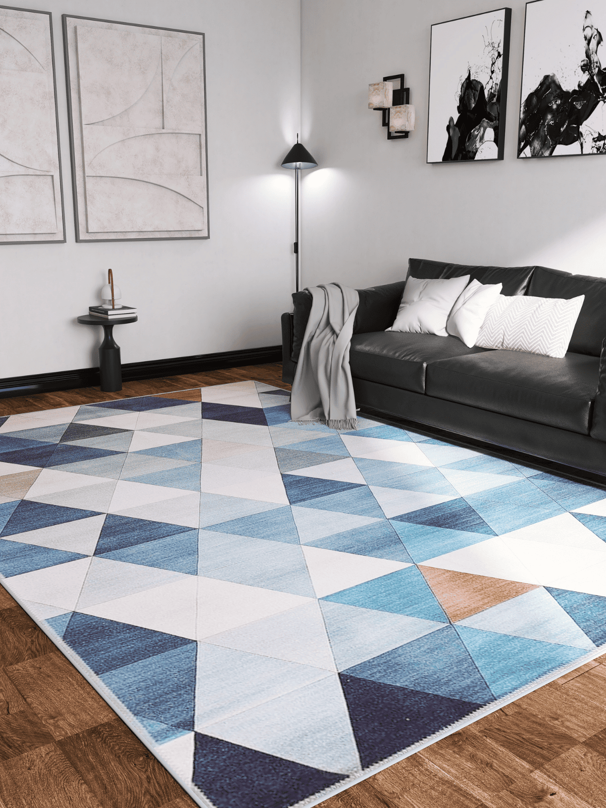 A modern living room with a black sofa, white and patterned pillows, gray blanket, wall art, and floor lamp on wood flooring features the Cubism Collage Blue Washable Rug - MDJ008—perfect for high-traffic areas.