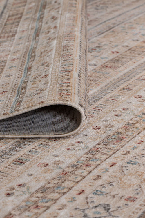 Load image 1 in gallery view. Beige area rug with a distressed striped pattern featuring small red and blue floral accents, shown with a curled corner.