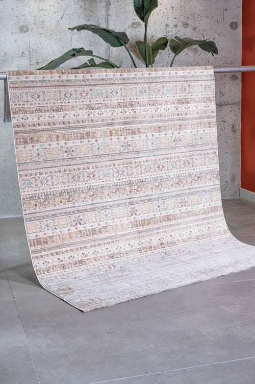Load image 1 in gallery view. Beige and cream rug with horizontal bands of geometric and floral patterns in blue and rust, draped over a metal bar.