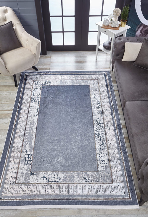 Load image 1 in gallery view. A modern living room featuring the Dramatic Boundaries - Washable Rug - JR1810 (Custom Size) in blue and gray, ideal for high-traffic areas, with a beige armchair, gray sofa, white side table with plants, and large windows in the background.