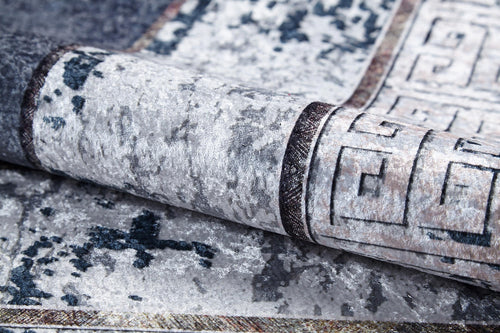 Load image 1 in gallery view. A close-up of the Dramatic Boundaries - Washable Rug - JR1810 (Custom Size) in gray and white with a distressed geometric border, ideal for high-traffic areas, features one corner folded to show the underside.