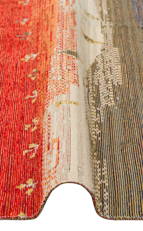 Load image 1 in gallery view. A close-up of the Dust Trace - Kilim - NMD12 shows a wavy fold, highlighting its gradient red, beige, and blue tones with subtle geometric and dotted patterns woven into the modern rug.