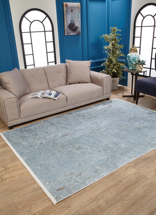 Load image 1 in gallery view. A modern living room with a beige sofa, open magazine, potted plant, blue paneled walls with arched windows and a painting. The light wood floor features the Earthy Sands - Washable Rug - JR1819 (Custom Size), ideal for high-traffic areas.