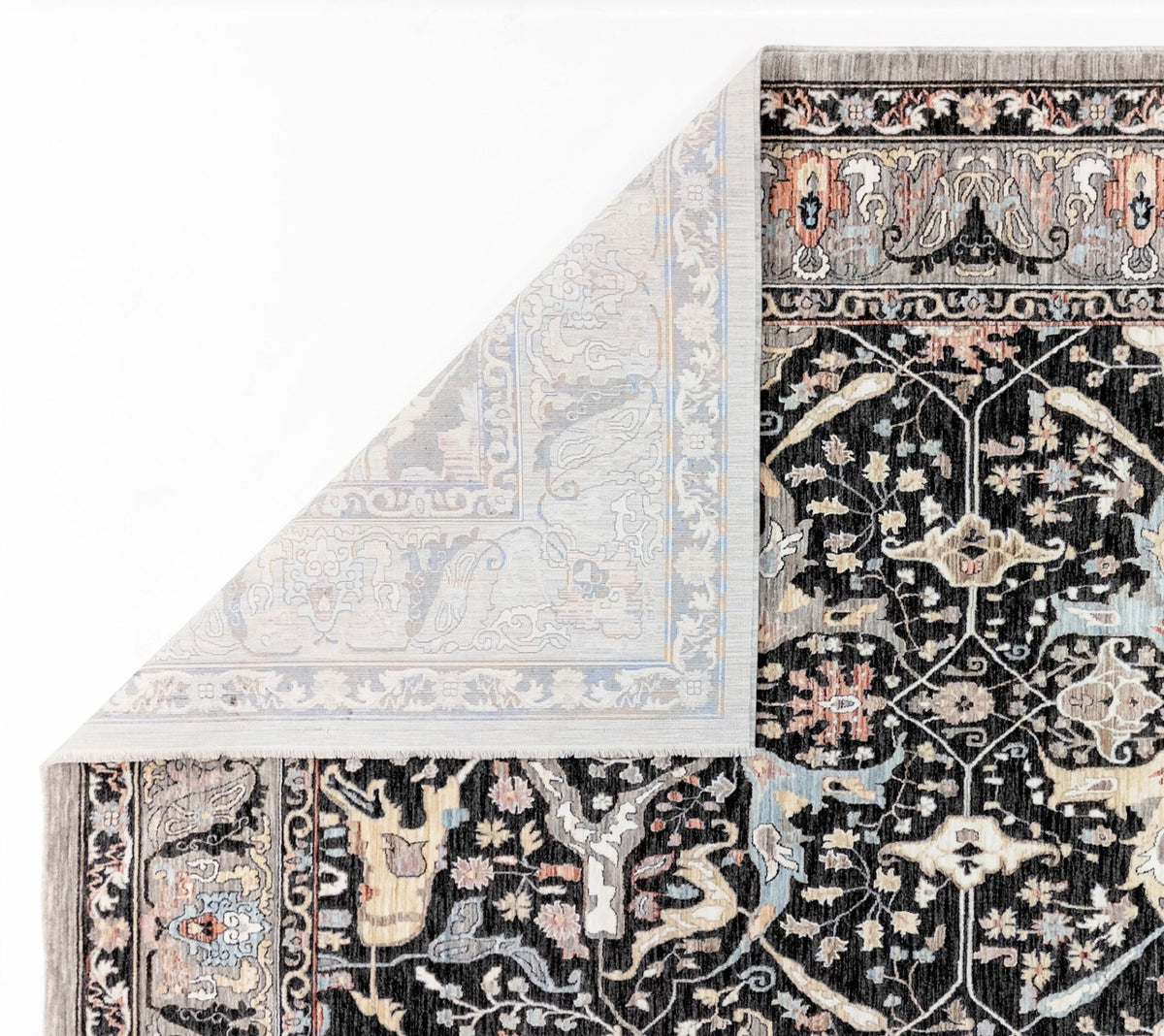 Black traditional rug with intricate floral patterns in cream, grey, and muted orange, shown with a folded corner.