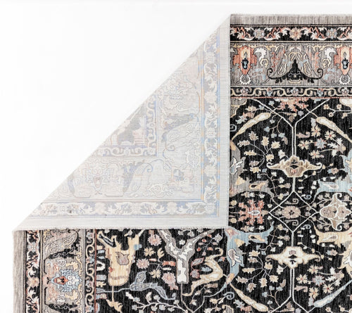 Load image 1 in gallery view. Black traditional rug with intricate floral patterns in cream, grey, and muted orange, shown with a folded corner.