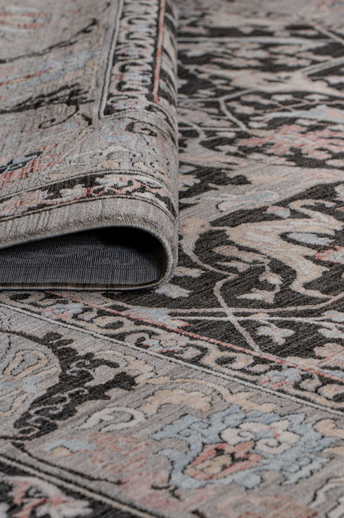Load image 1 in gallery view. Charcoal, grey, and muted pink traditional floral medallion rug with a folded corner showing the pile and backing.