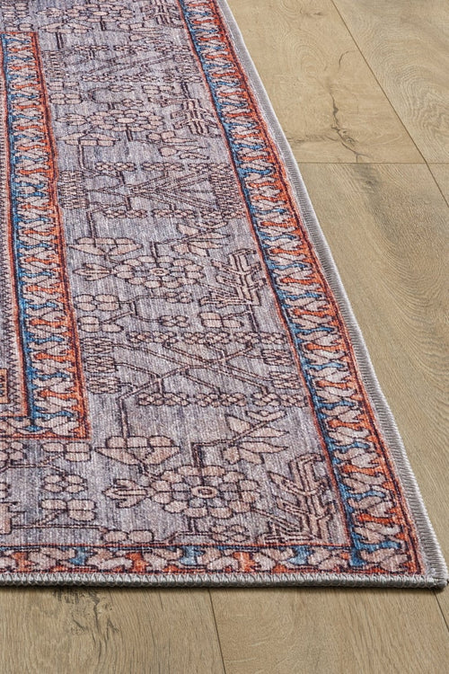 Load image 1 in gallery view. The Echelon Bordered Washable Rug - LCC3018 features a faded purple and red geometric floral pattern with blue and orange borders—perfect for high-traffic spaces and striking on light wood floors.