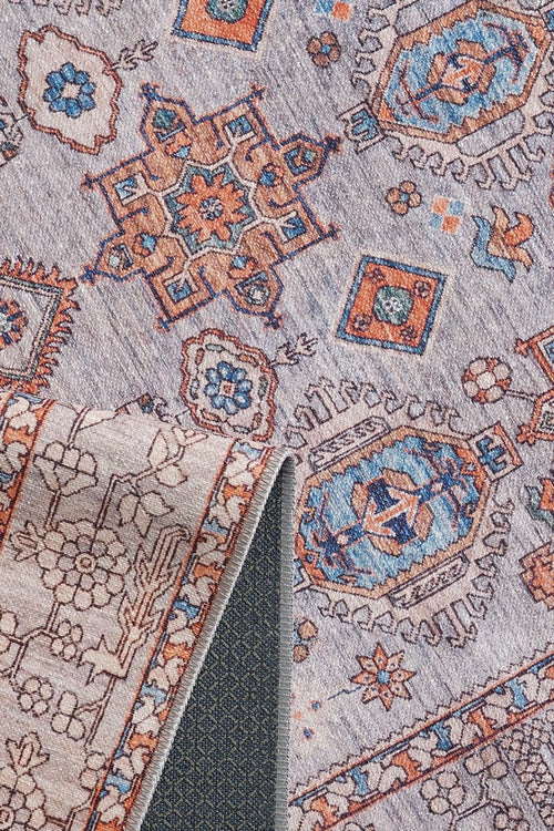 Load image 1 in gallery view. A close-up of the Echelon Bordered Washable Rug - LCC3018 (Custom Size) in blue, orange, and beige with geometric and floral designs; one corner is folded to show the underside and rug pad—perfect for high-traffic areas.