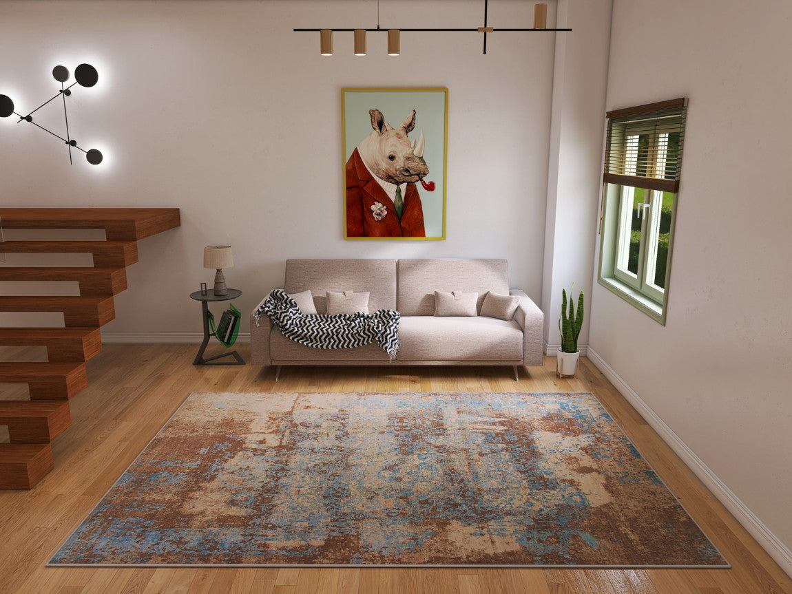 A modern living room with a beige sofa, patterned throw, potted plant, large window, wooden staircase, and abstract animal wall art features the Enchanted Threads - Washable Rug - JRS002 (Outlet) US in bronze and brown tones on the wooden floor.