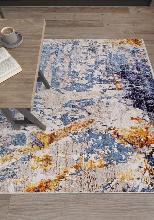 Load image 1 in gallery view. The Enigmatic Elegance - Washable Rug - JR787 (Custom Size), featuring vibrant blue, yellow, and white patterns, is placed on a light wood floor near a wooden table with an open book and coffee—ideal for high-traffic areas.