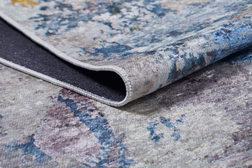 Load image 1 in gallery view. A close-up of the Enigmatic Elegance - Washable Rug - JR787 (Custom Size) shows its folded corner, revealing textured blue, gray, and beige tones—durable and washable for high-traffic areas, with a glimpse of its dark underside.