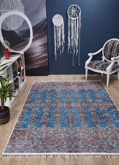 Load image 1 in gallery view. A cozy room with the Ethereal Essence - Washable Rug - JR5087 (Custom Size) in blue for high-traffic areas, a white armchair, gray cushion, potted plant, bookshelves, lantern, and white dreamcatchers on a dark blue wall with a light wood floor.