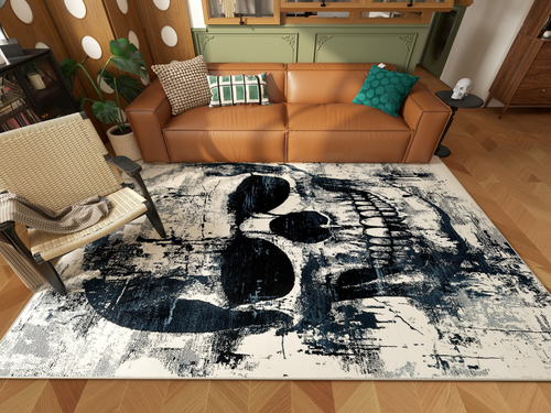 Load image 1 in gallery view. A modern living room with a brown leather sofa, green pillows, a potted plant, and a woven chair. The floor showcases the Faded Skull - Washable Rug - HLW008 featuring a bold black skull on a distressed white background.
